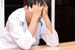 doctor with head in hands